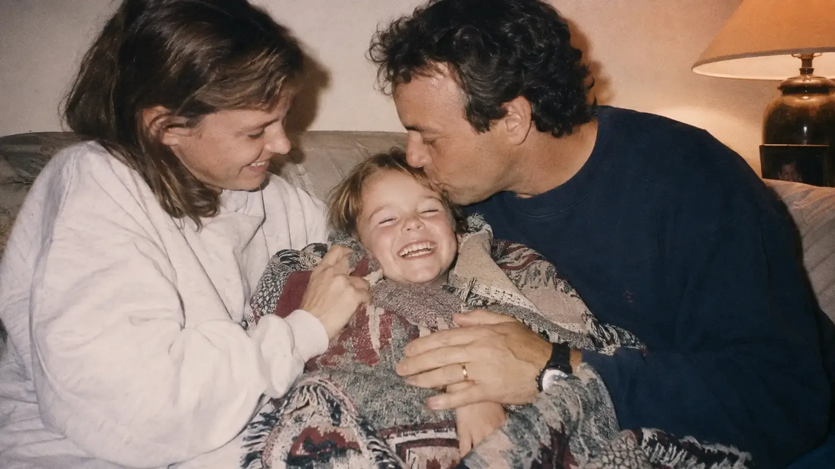 Parents caring for their laughing child on the sofa at home