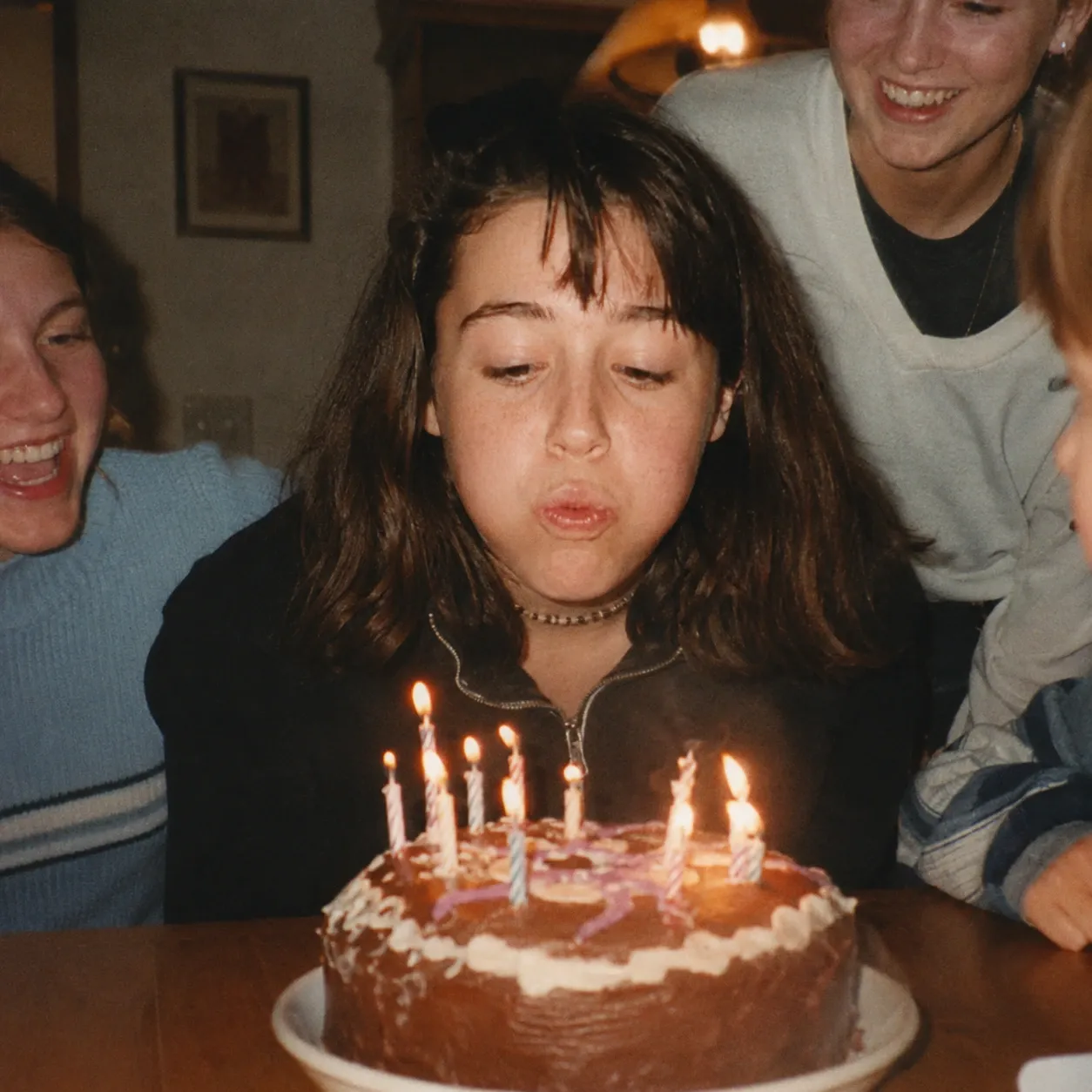 Blowing out candles on a homemade birthday cake among friends